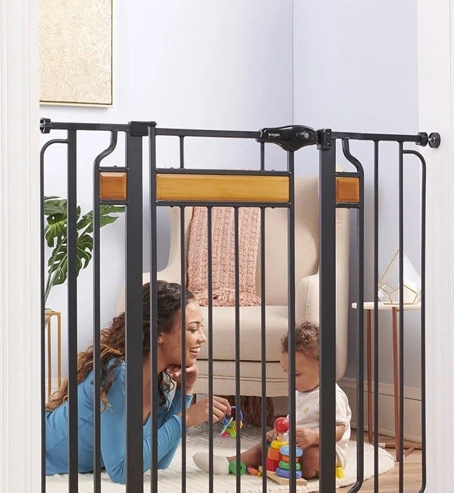 Woman and baby playing together behind the safety gate