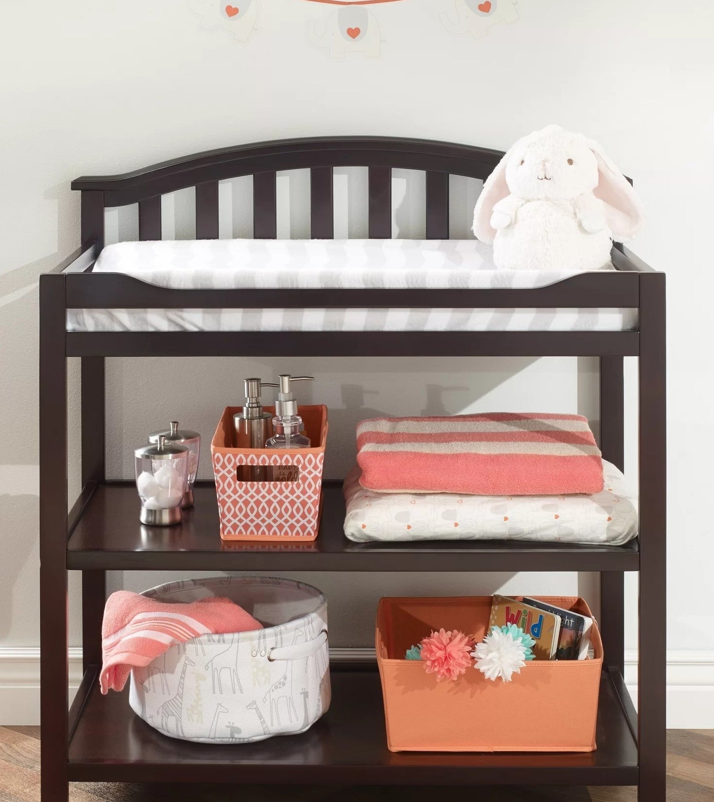Espresso changing table on wood floor storing baby accessories