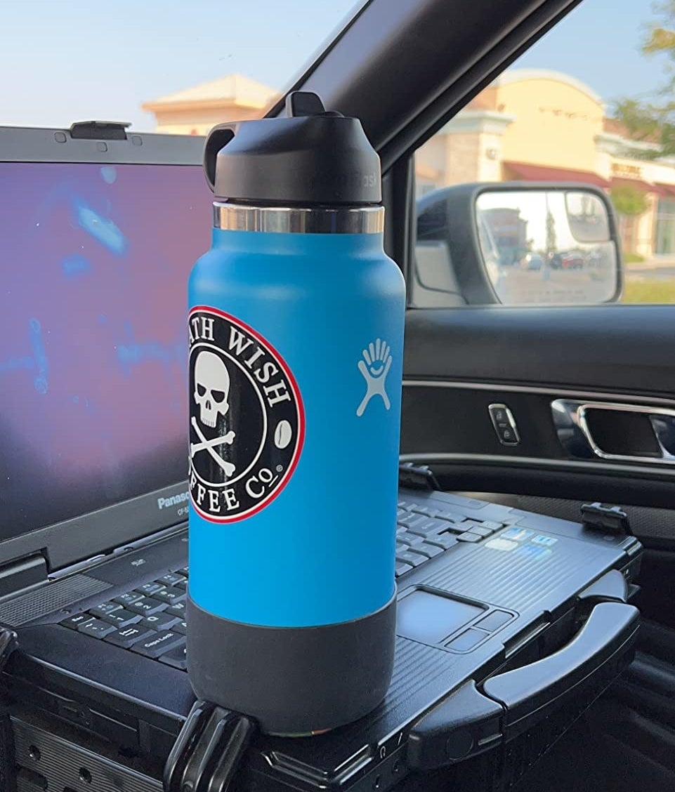 Reviewer&#x27;s blue hydroflask with skeleton death wish coffee co sticker on it, resting on top of computer in car