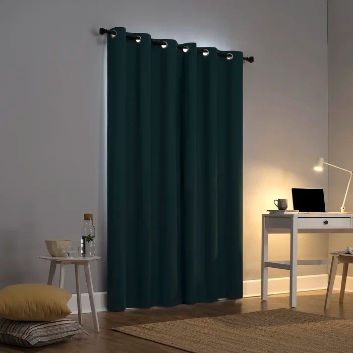 A blackout curtain in a room next to a desk