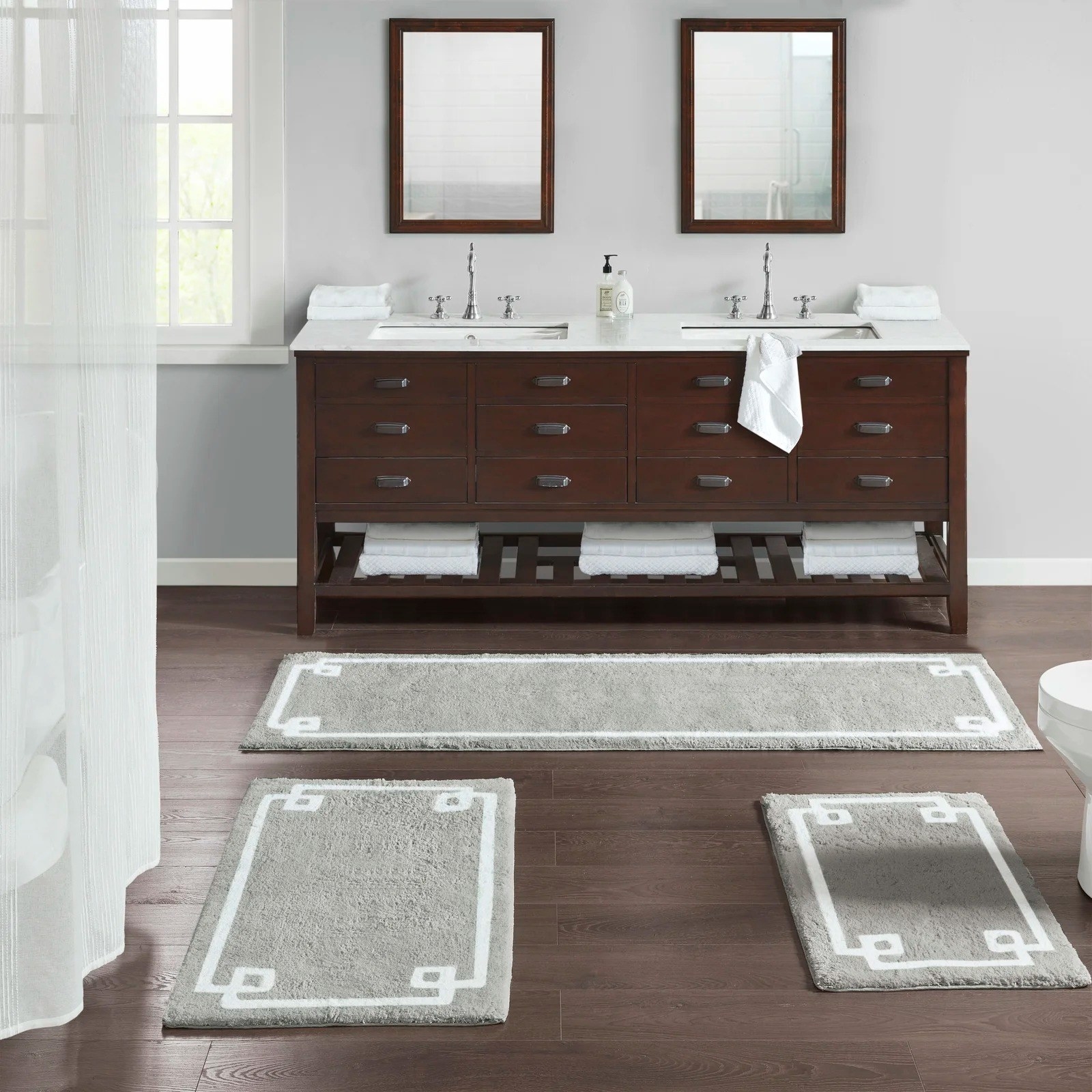 Cotton bath rugs on a wood bathroom floor.