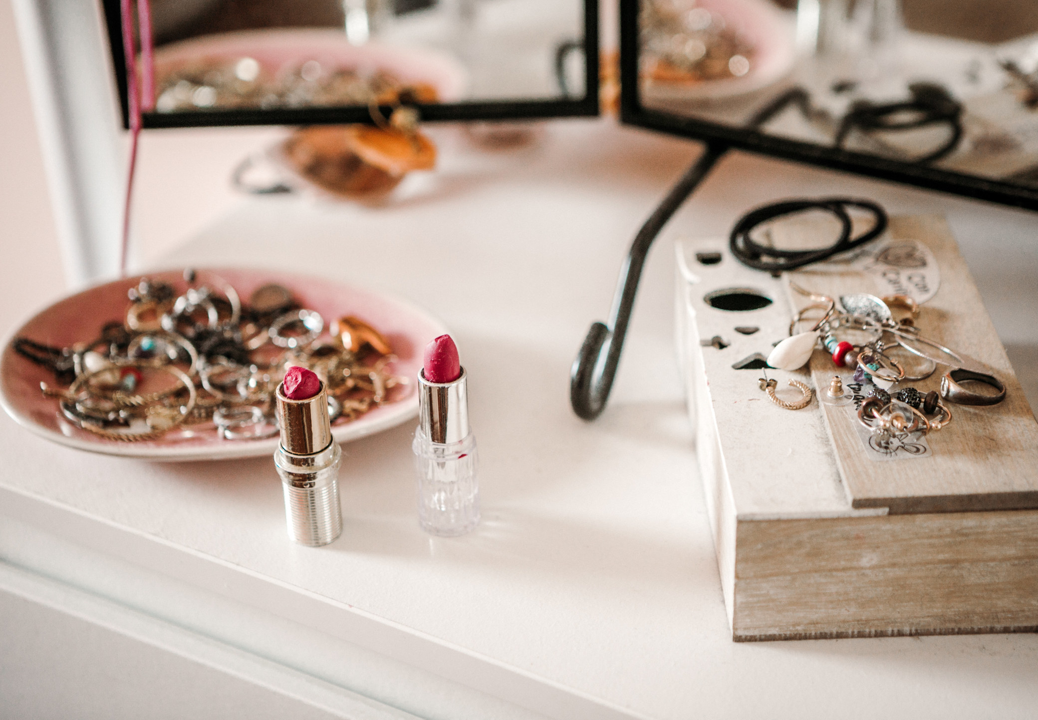 a dresser top covered in jewelry and makeup