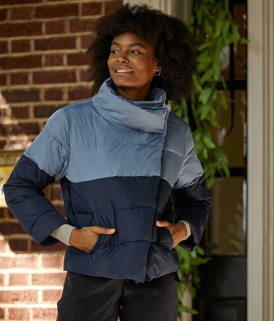 model in color blocked light and dark blue puffer jacket with a large collar