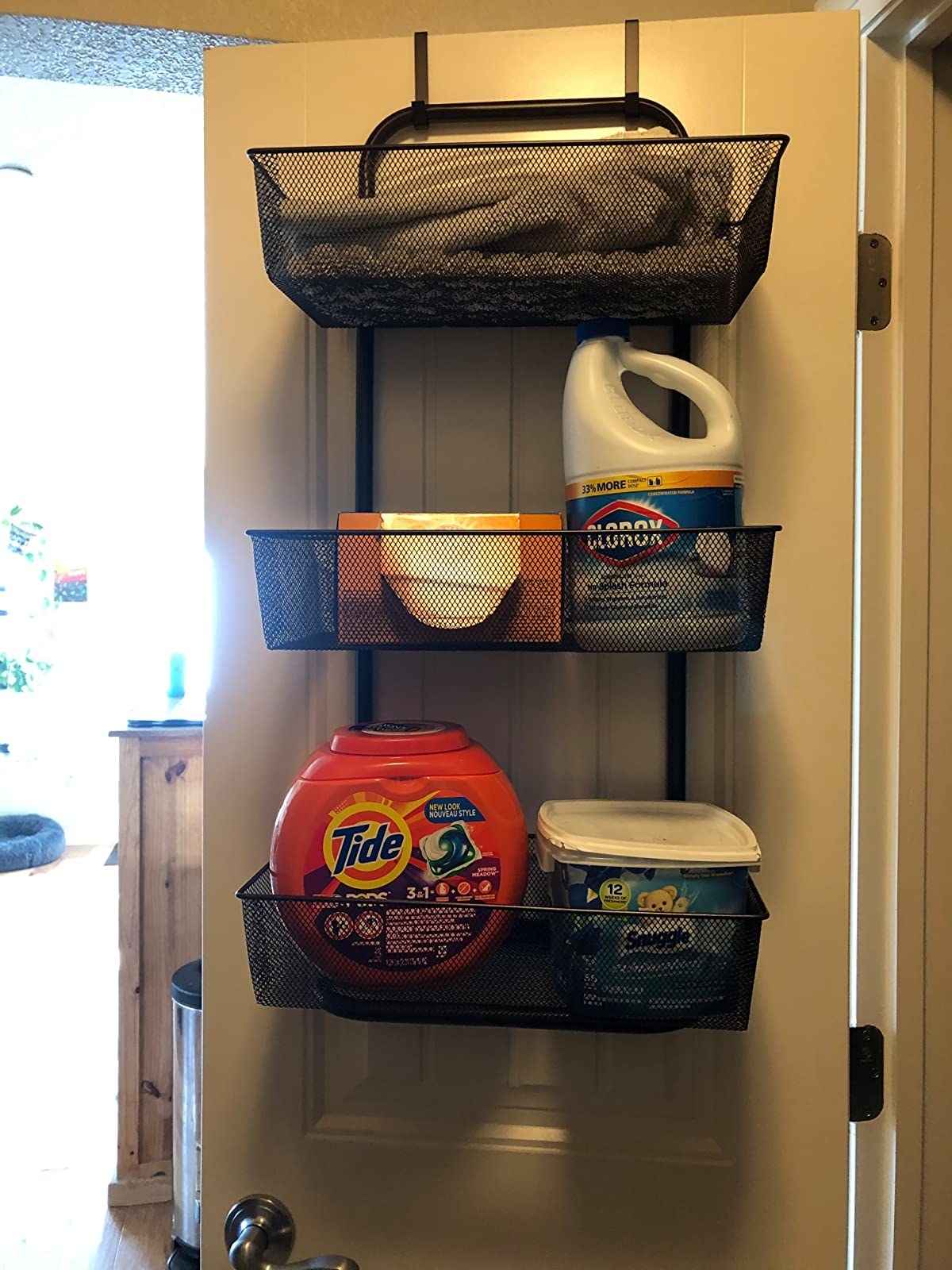 reviewer image of the brown organizer hanging behind a door housing laundry room necessities