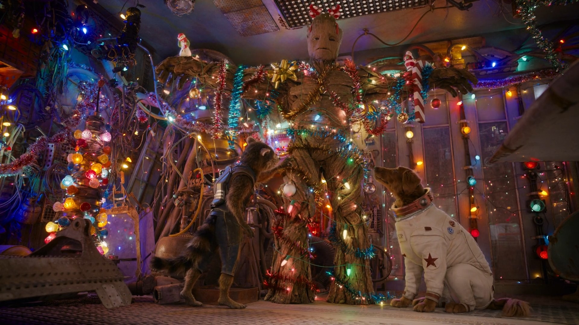 Rocket and Cosmo hang Christmas decorations from Groot