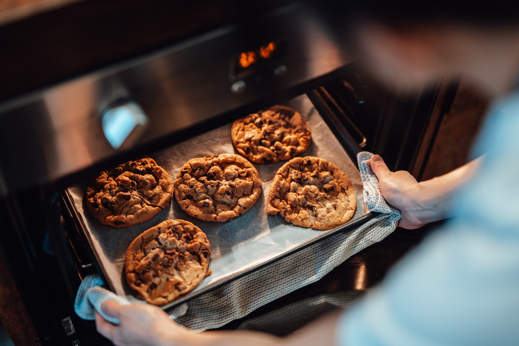 A woman taking out freshly baked cookies from the oven