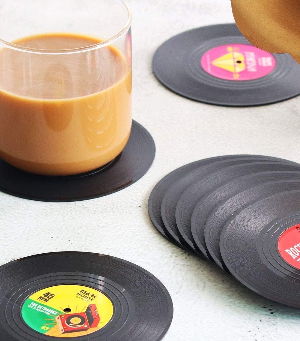 Several record coasters on a table, one has a mug filled with coffee on it