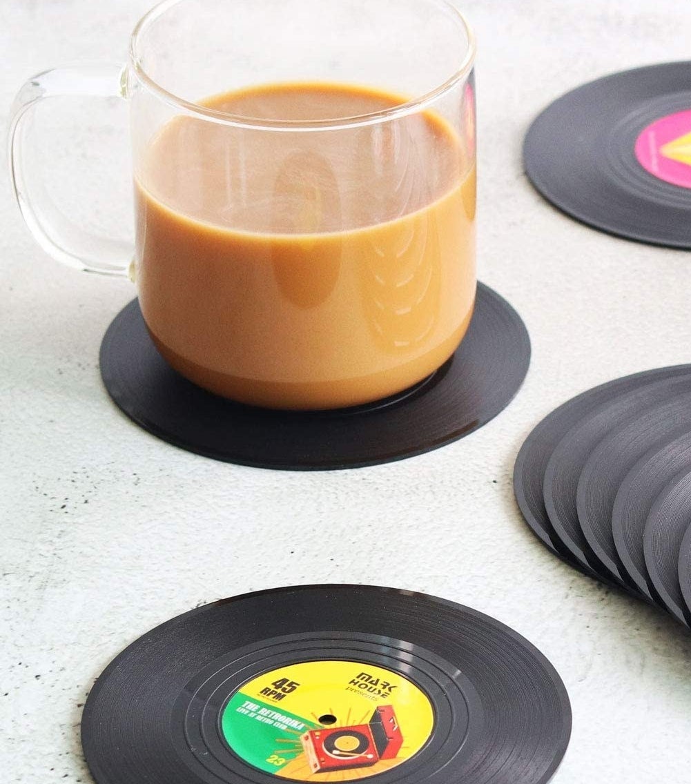 Several record coasters on a table, one has a mug filled with coffee on it
