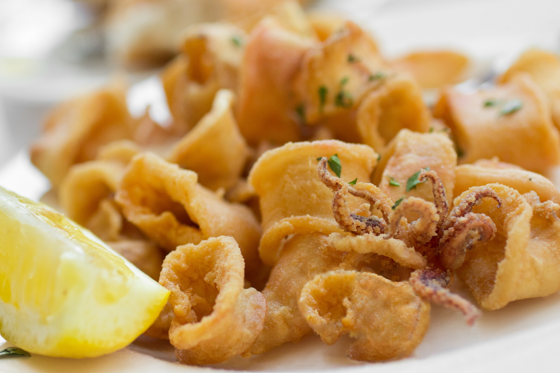 Traditional Italian style fried calamari with a wedge of lemon on the side.