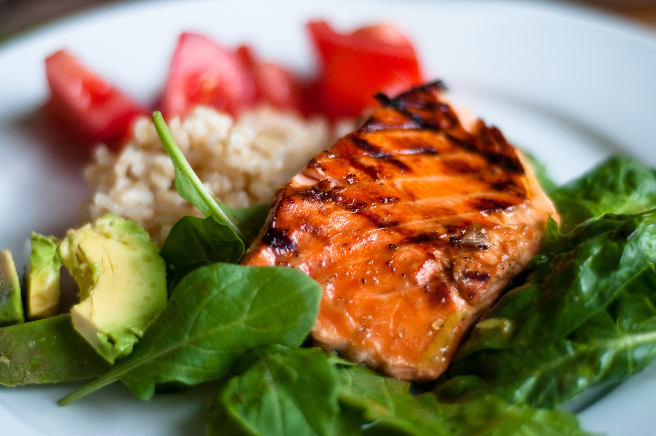 Salmon over lettuce with avocado.