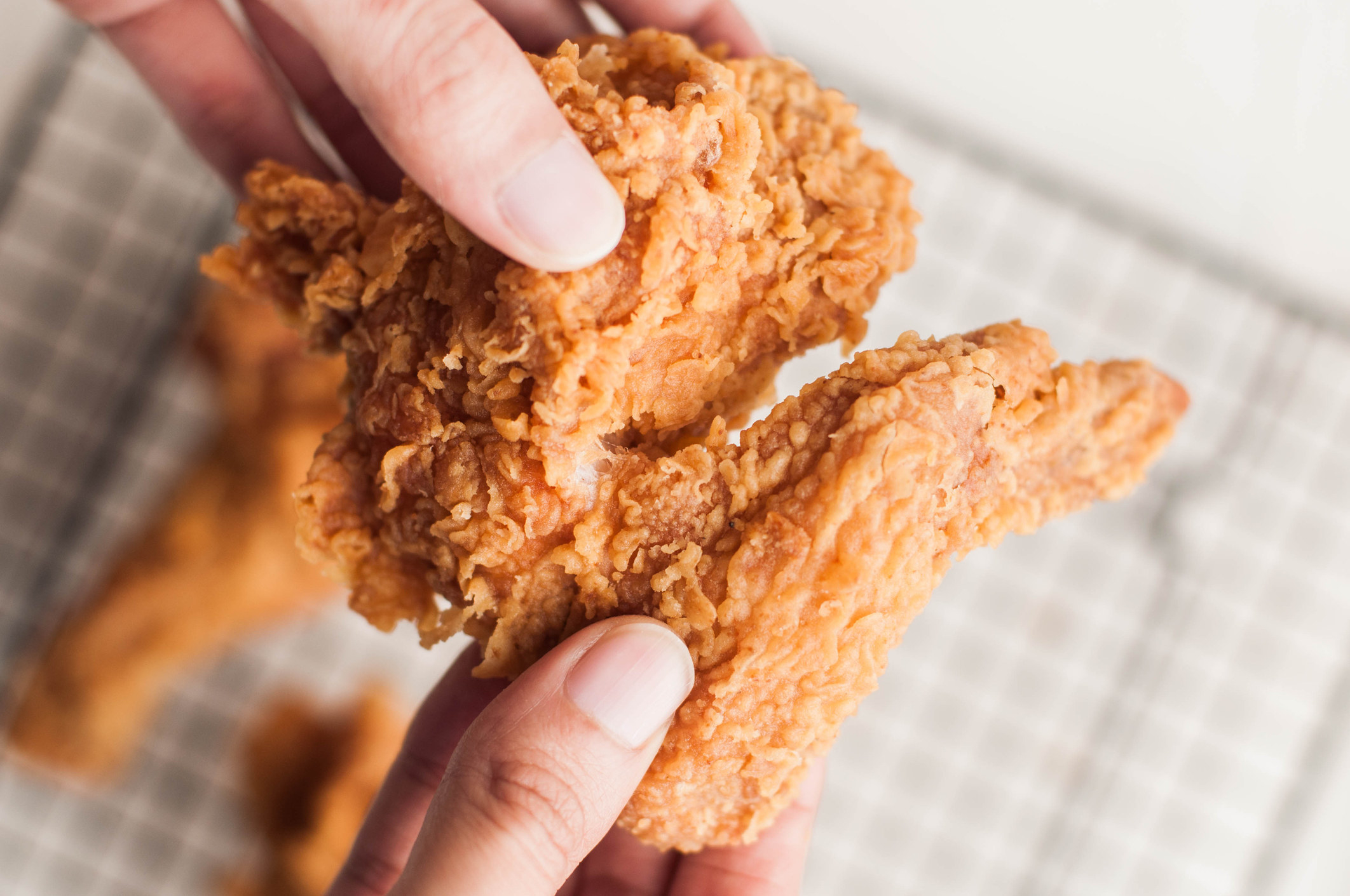 A person holding a fried chicken wing.