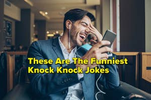 Youn man with smartphone and headphones sitting in cafe and laughing