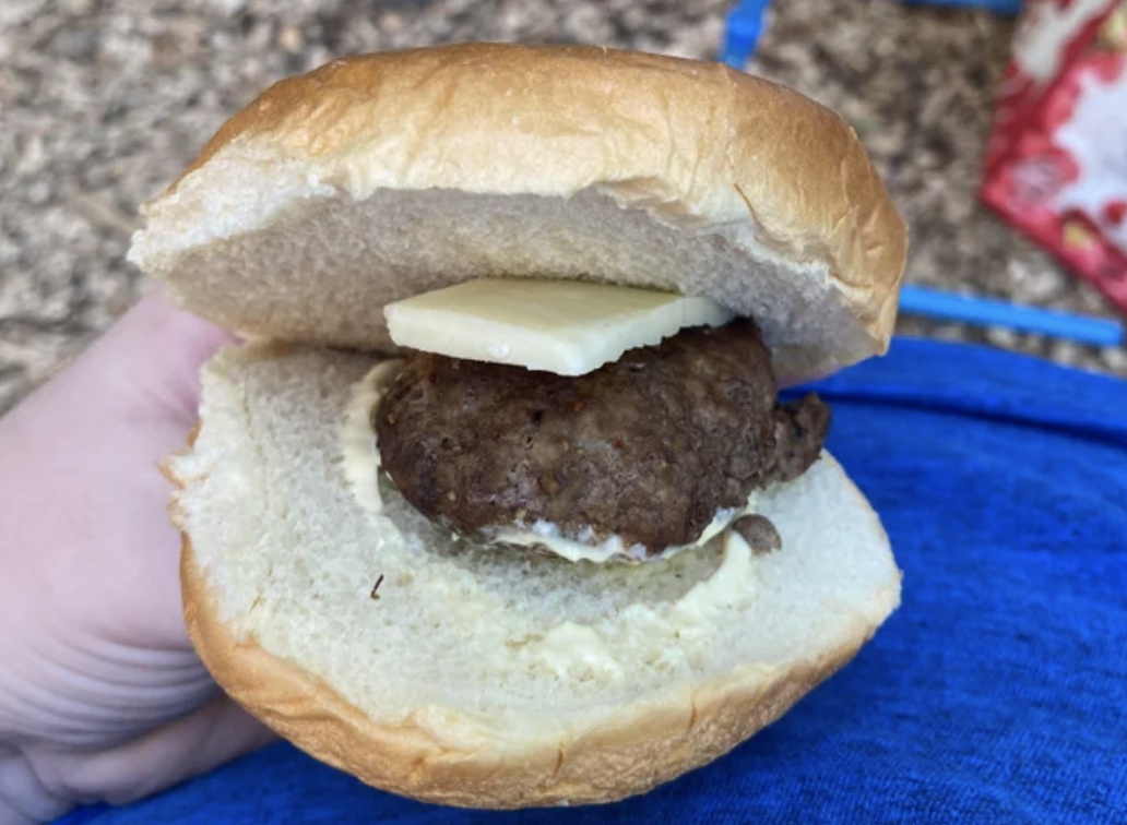 a hamburger with a small patty covered in butter