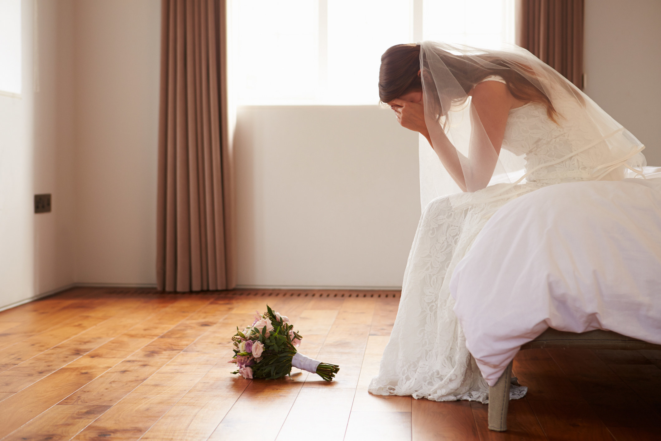 A bride crying with her bouquet on the floor