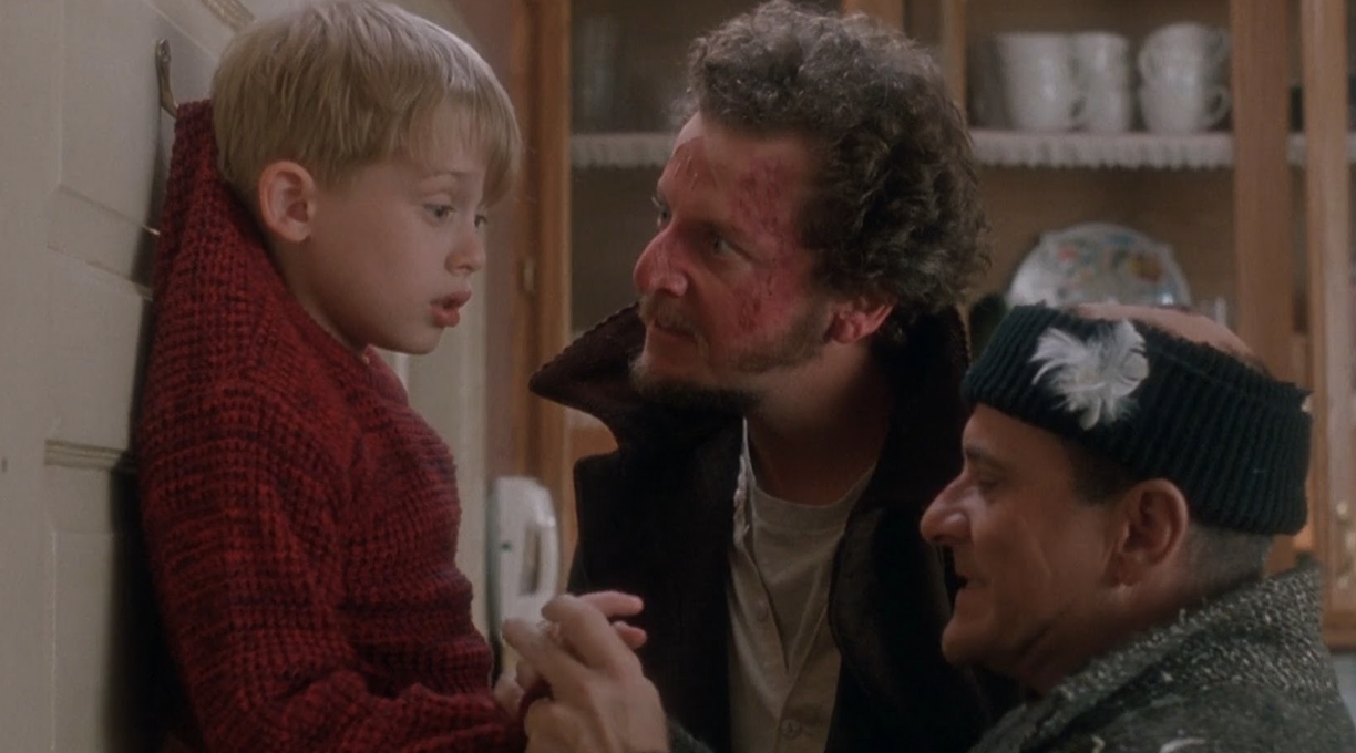 kevin mcallister being held on a door hook by marv and harry in home alone