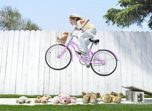 A kid jumping over teddy bears on a bike
