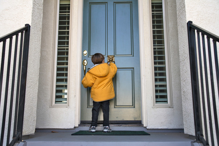 A little boy knocking on someone&#x27;s door