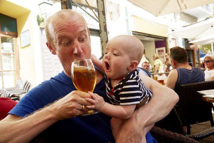 A father drinking while holding his baby