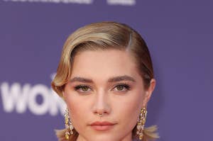 Florence Pugh wears a melon-colored dress with a cutout above the stomach and thin straps and dangling gold earrings.