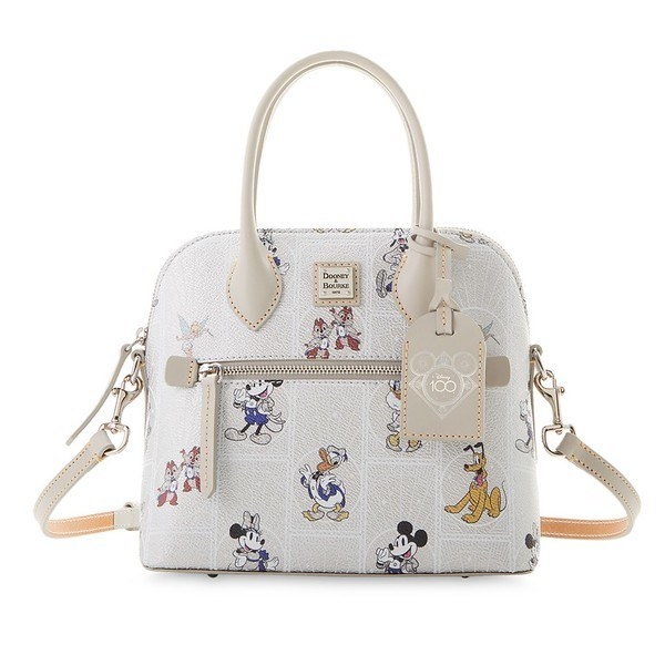 An off white satchel bag with handles and shoulder strap featuring an allover pattern with mickey, minnie, donald, pluto, goofy, and chip and dale in their 100th anniversary outfits