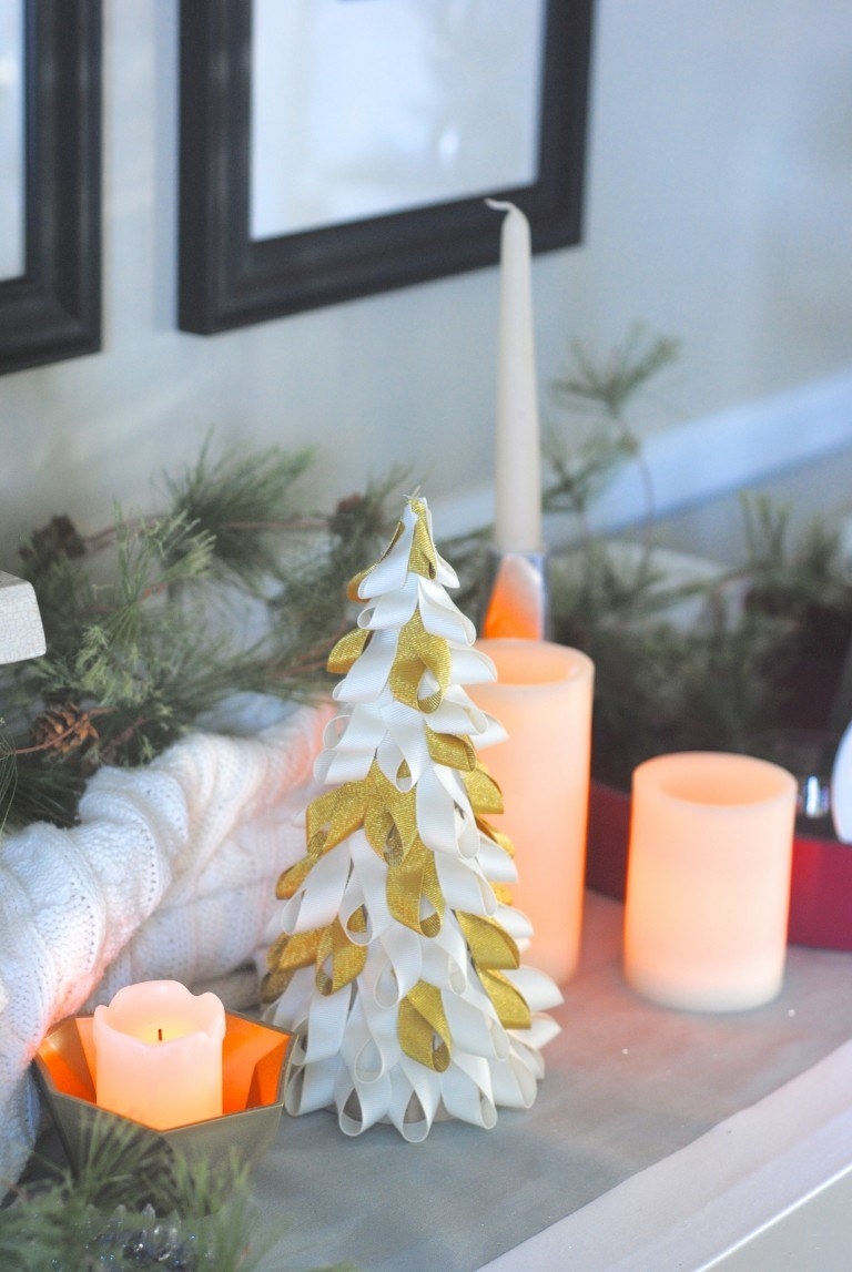 a mini Christmas tree made out of ribbons next to candles