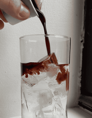 gif of pouring coffee concentrate into drinking glass with ice and water