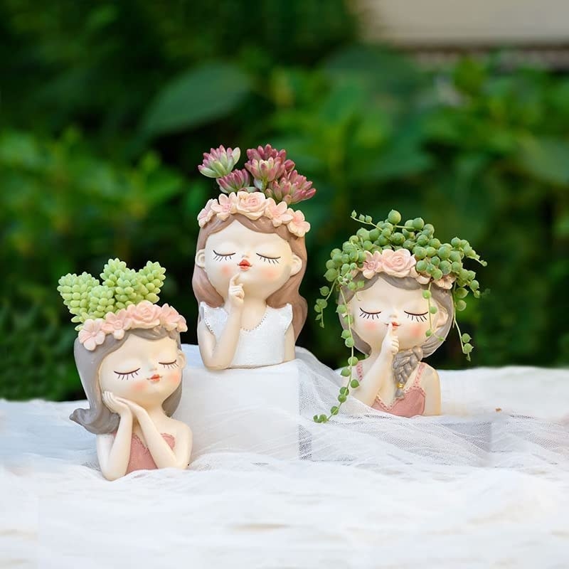 three fairy head planters with succulents in them