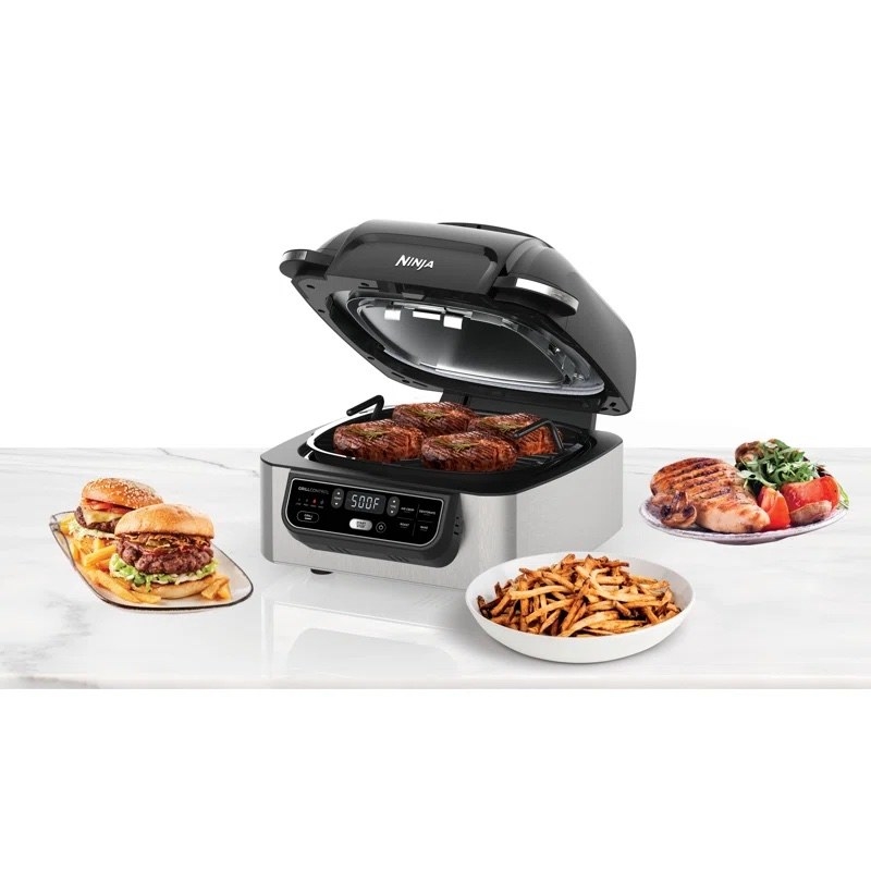 ninja foodi 5-in-1 indoor grill with meet on the grill and plates of food next to it