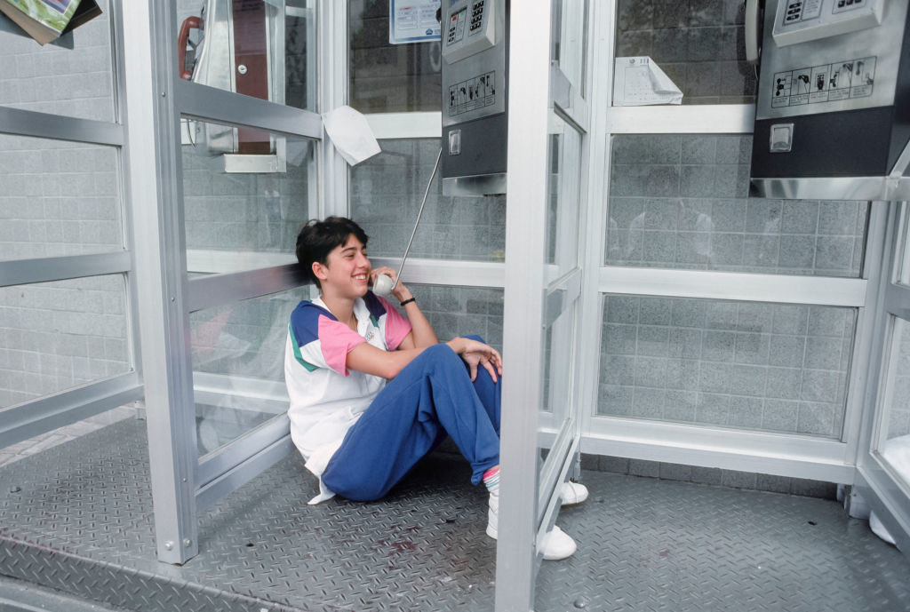 man sitting down in a phone booth having a long conversation