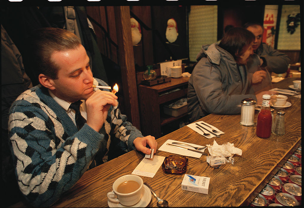 man lighting a cigarette inside a restaurant