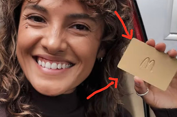 A smiling woman holding a gold card with a McDonald's logo on it