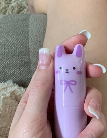 reviewer holding a purple bunny perfume stick