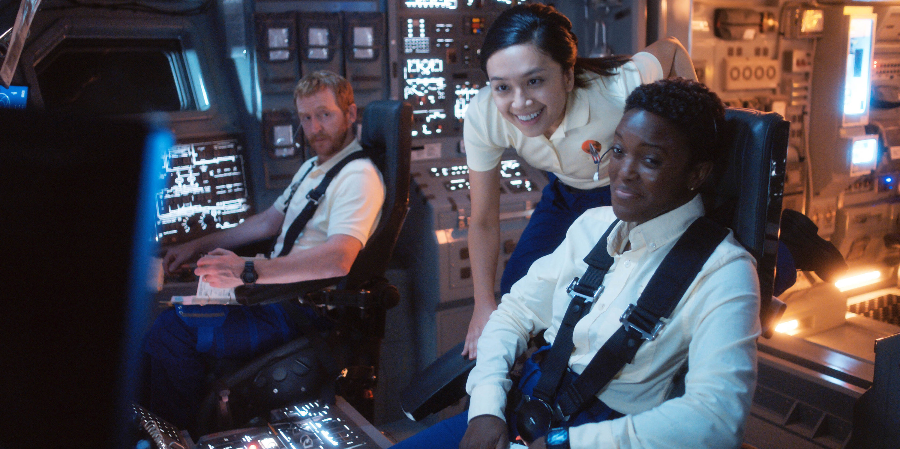 Three characters sitting in a control room