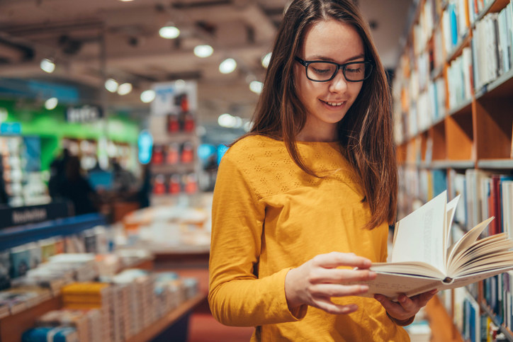 A young girl in a bookstore flipping through a book