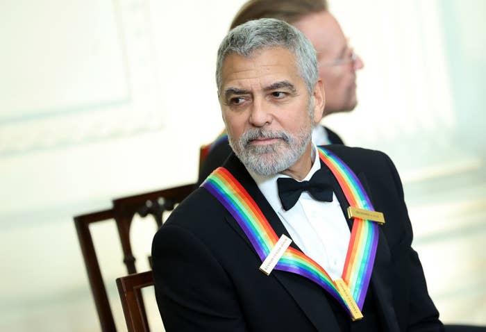 George Clooney in a tux and wearing a rainbow sash around his neck