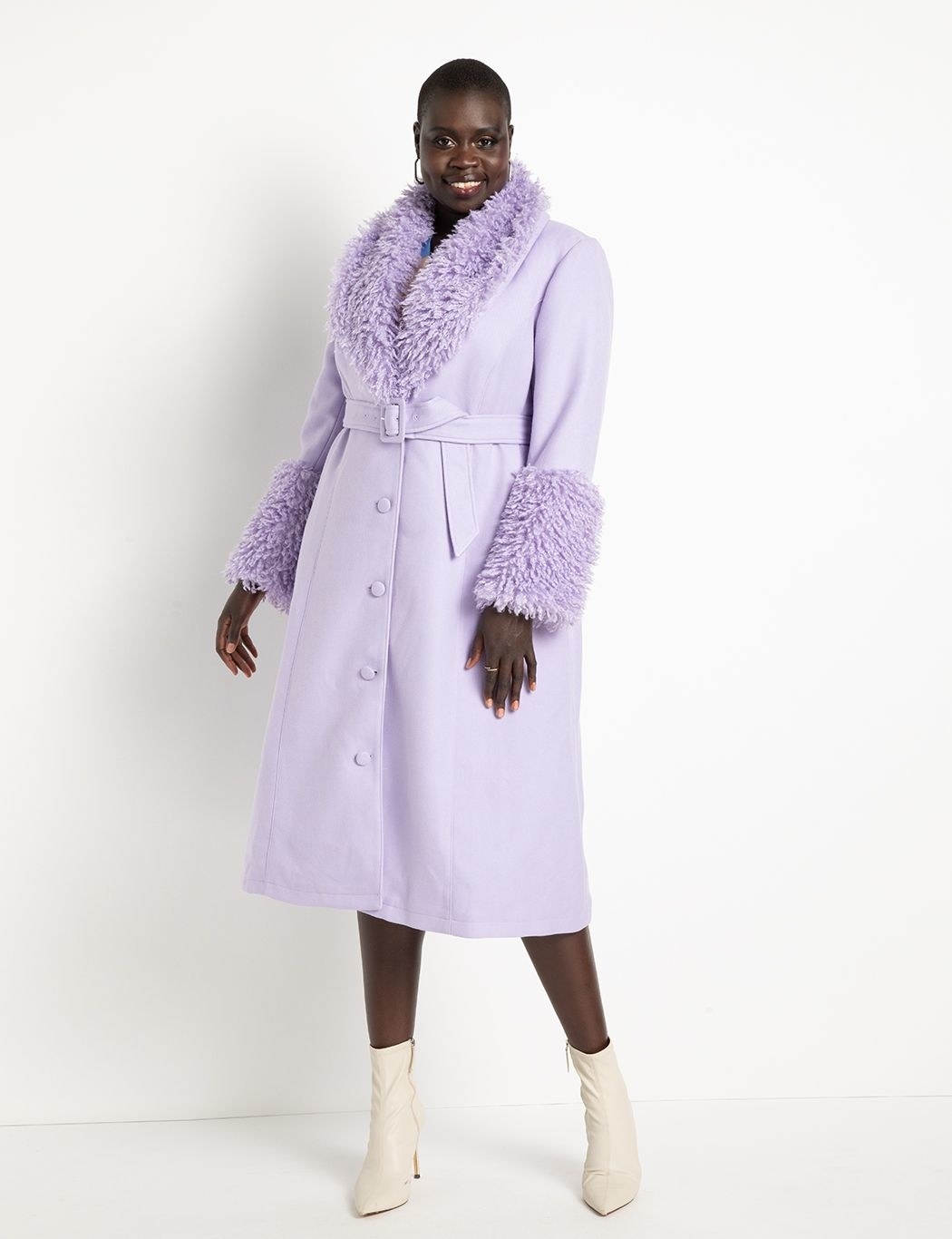 model in light purple long coat with a waist tie and purple faux fur trim on the cuffs and collar