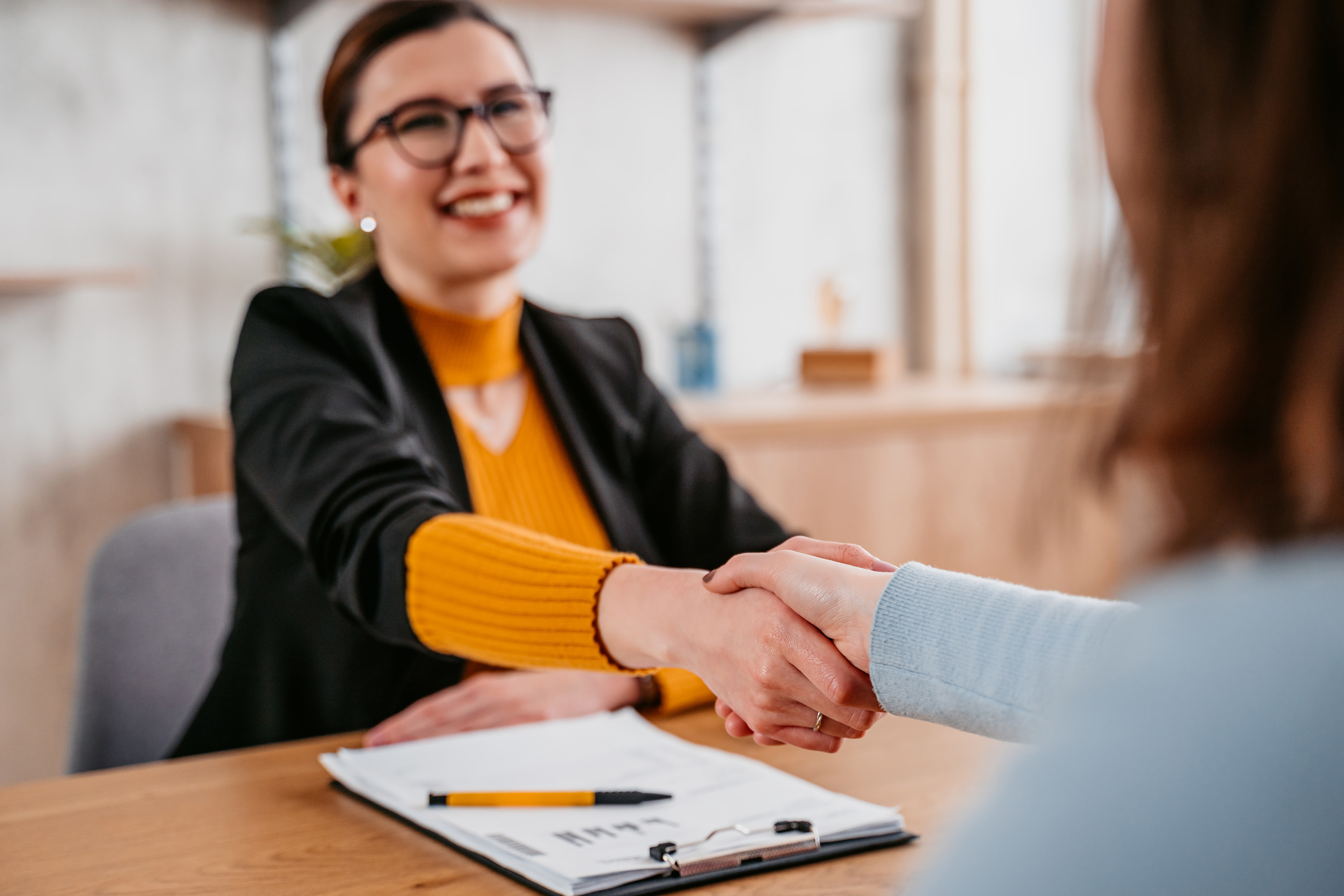 Woman shakes hands over a desk