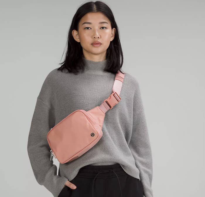 A person wearing the bag crossbody-style over a sweater