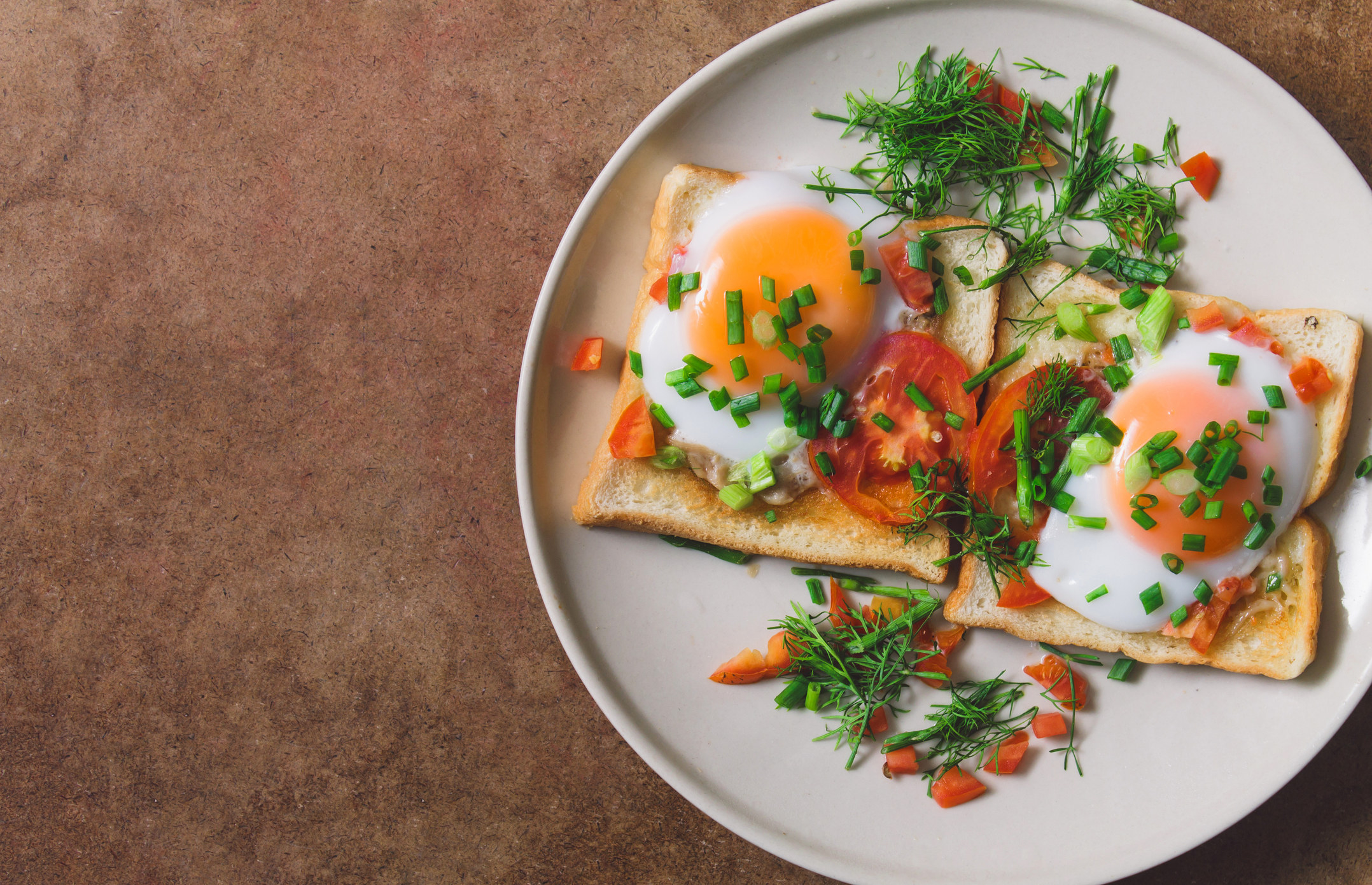 Toast topped with sunny side up eggs and veggies.