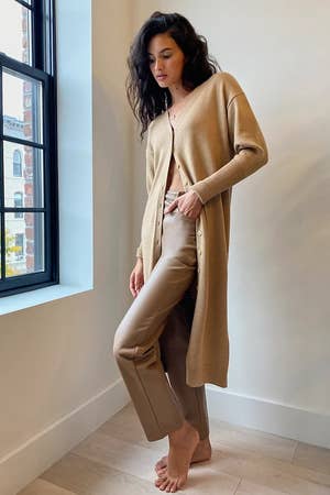 a model wearing the camel colored sweater dress over pants