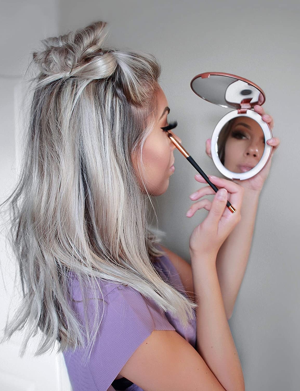 A person using the compact while doing their makeup