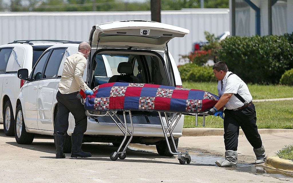 Men loading a body into a hearse