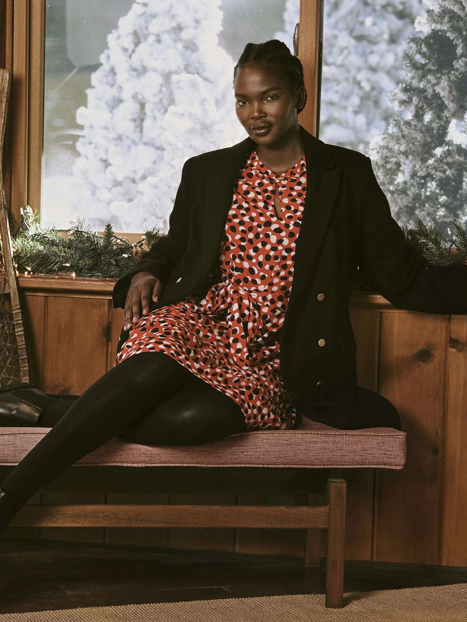 a model wearing the red, white and black patterned dress with a black jacket