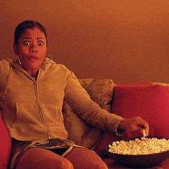 a woman watching TV and eating popcorn