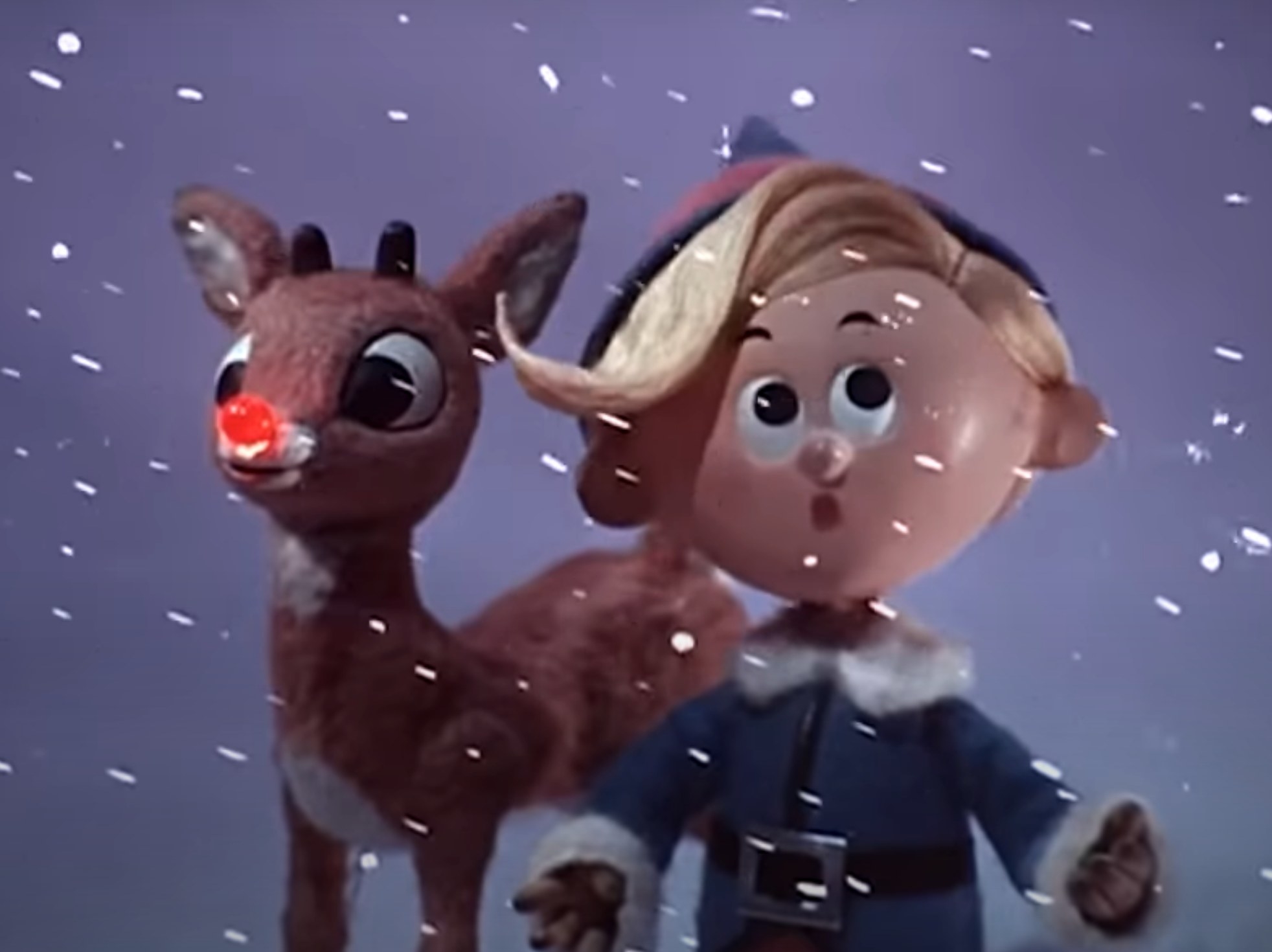Rudolph and Hermey stand in the snow