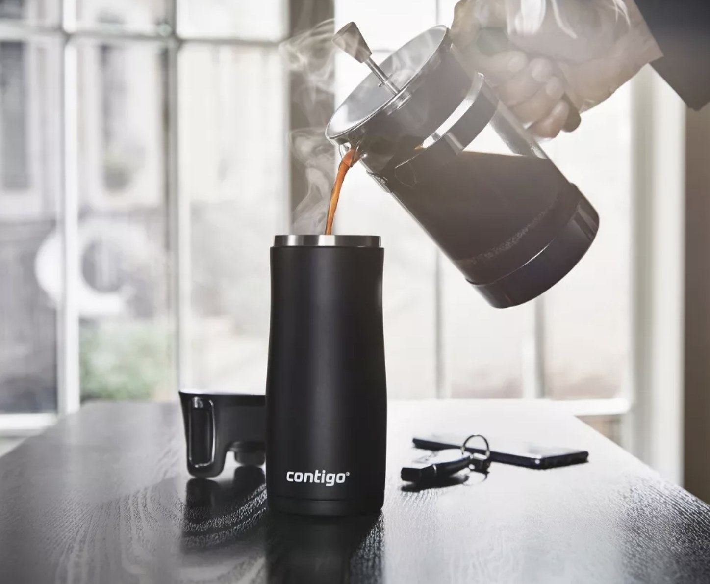 model pours French press coffee into Contigo travel mug