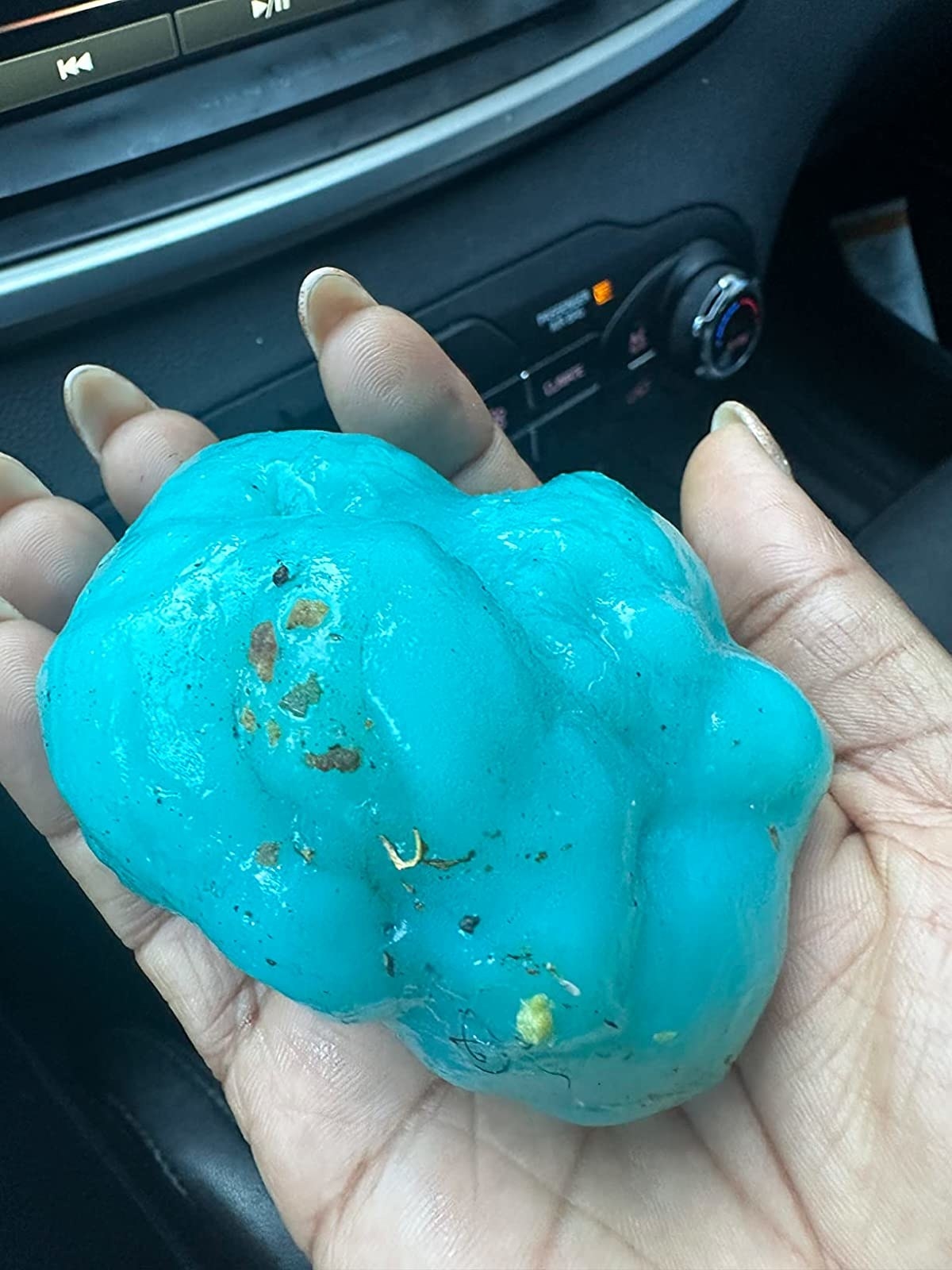 Reviewer holding cleaning gel in their car