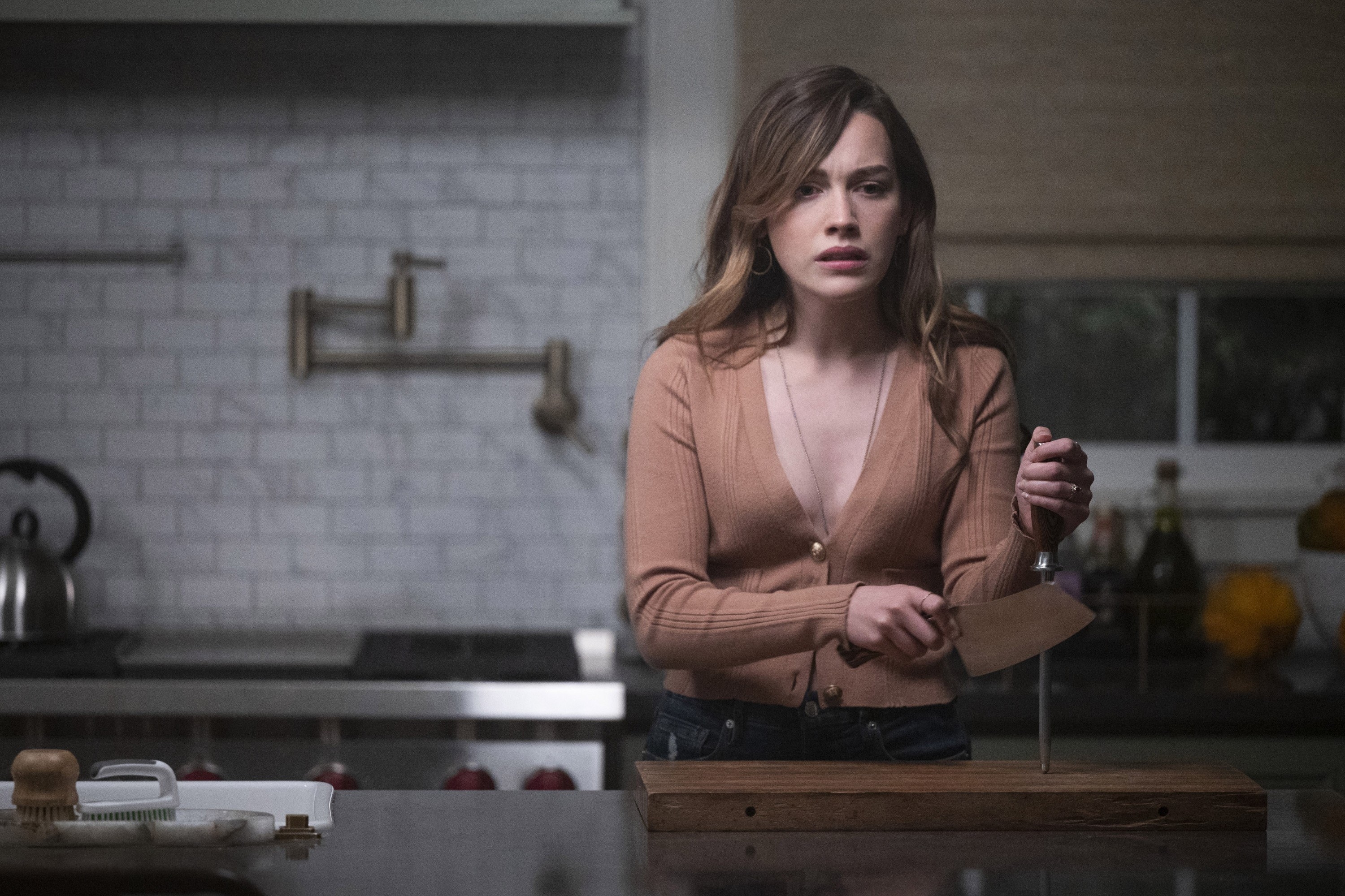 Love Quinn holding a butcher knife in a kitchen