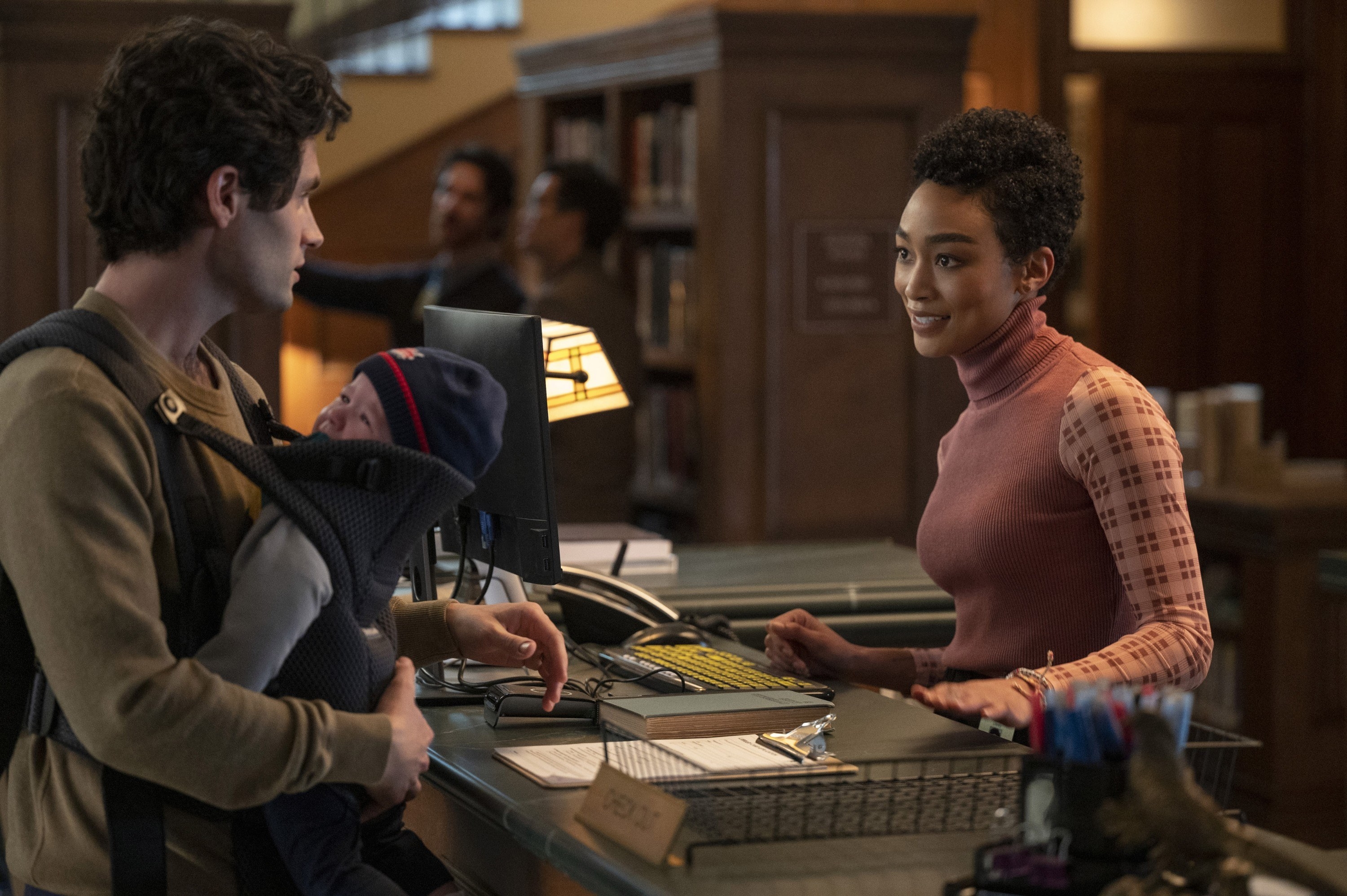 Joe with a baby talking to Marienne in a library