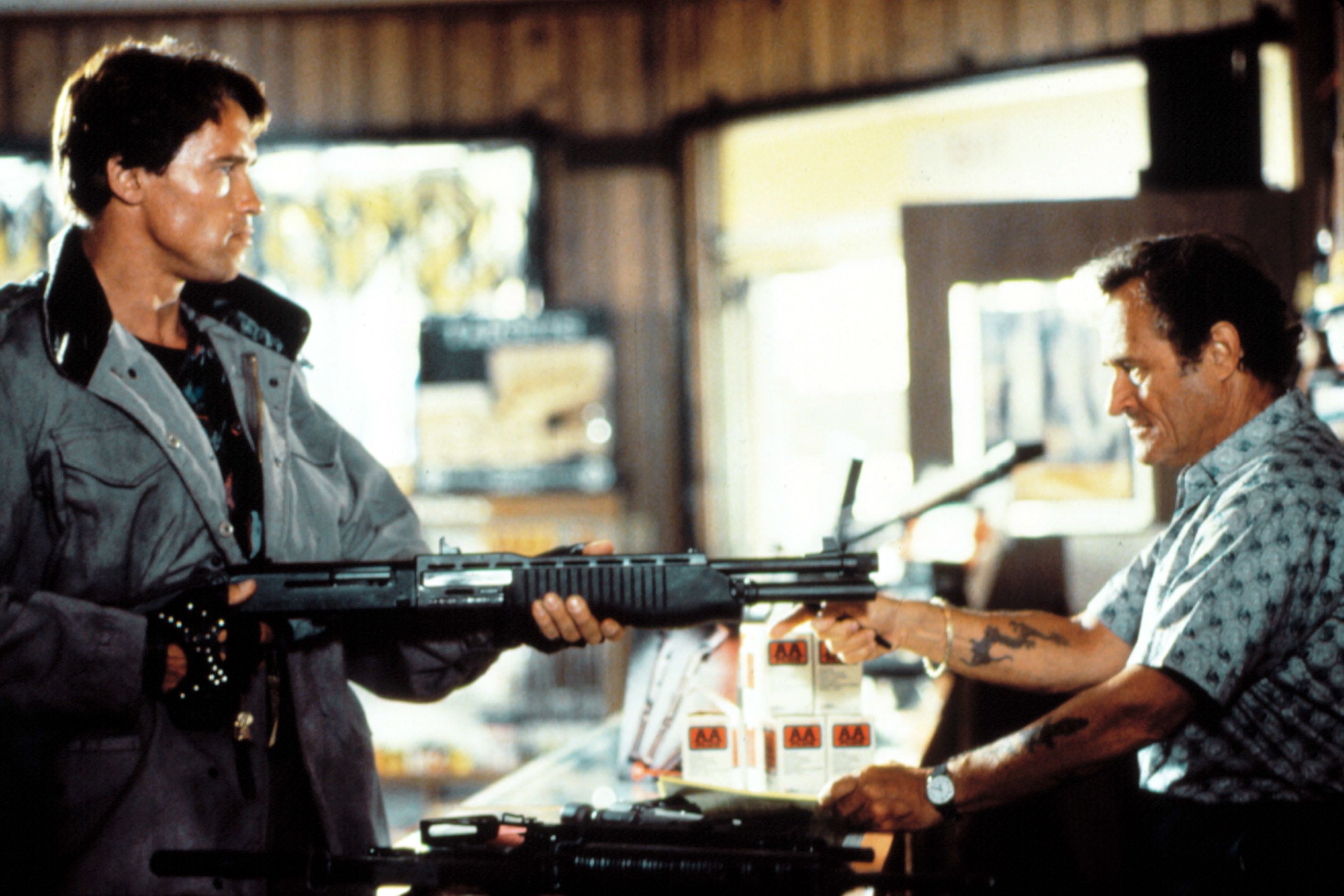 Arnold Schwarzenegger pointing a gun at Dick Miller.